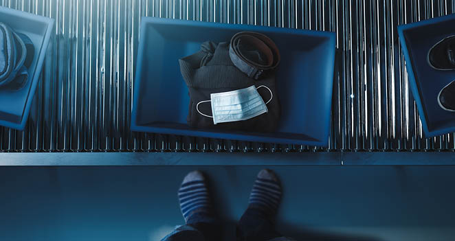 man in socks with carry-on items in bin at airport